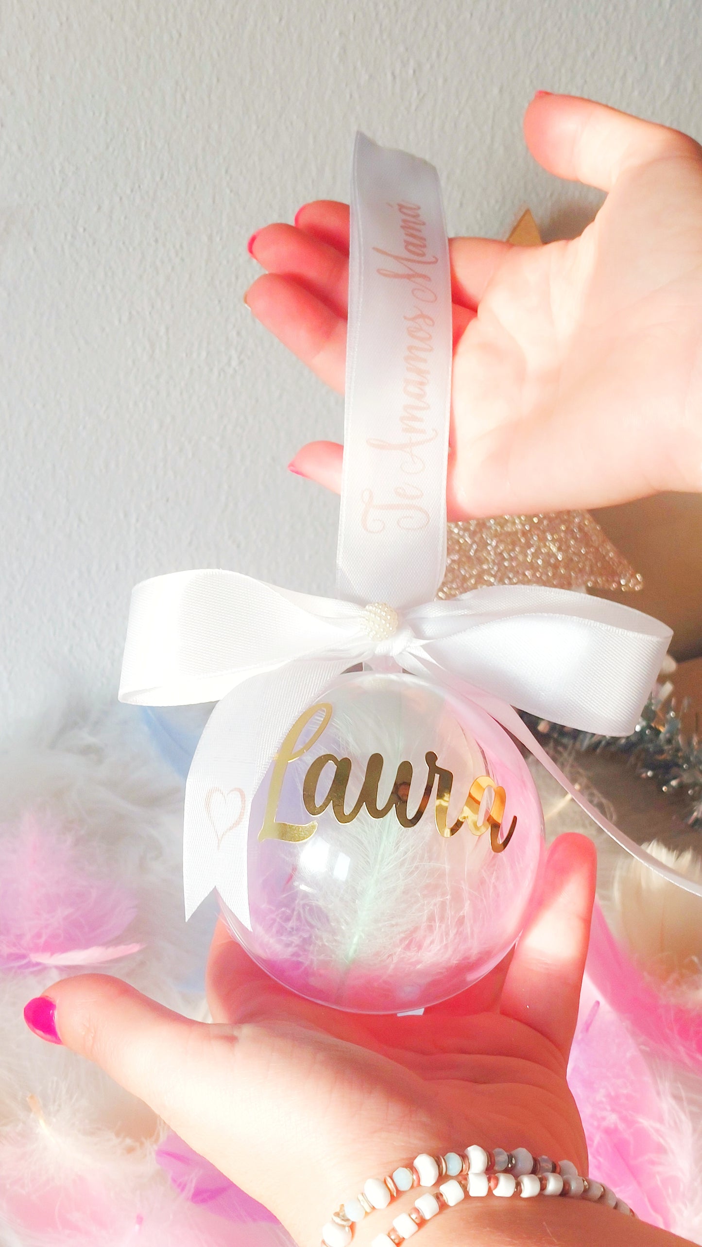 Bola adorno Navideña con plumas y cinta personalizada con frase y nombre dorado. Adorno personalizado para árbol navideño